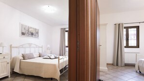 A bedroom with a bed, bedside table, lamp, and a painting on the wall.