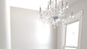 Una escalera con barandilla blanca, un candelabro y una ventana con persianas.