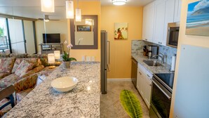 A modern kitchen with a marble countertop, stainless steel appliances, and a large window. - Amazing Ocean Front at Sugar Beach Resort #519, High End Remodel, 1Bed/1Bath (Kihei)