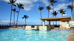 A swimming pool with clear blue water, surrounded by palm trees and a covered seating area. - Amazing Ocean Front at Sugar Beach Resort #519, High End Remodel, 1Bed/1Bath (Kihei)