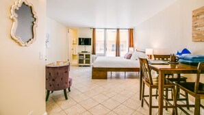 A hotel room with a bed, a dining table, a chair, a TV, and a window with curtains. - Queen Studio, Full Kitchen 1.5 mins from the Beach (Honolulu)