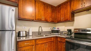 A kitchen with wooden cabinets, a stainless steel refrigerator, a microwave, a toaster, and an oven. - Queen Studio, Full Kitchen 1.5 mins from the Beach (Honolulu)