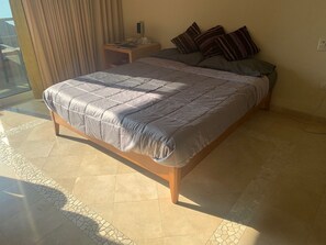 A hotel room with a large bed, a bedside table, a nightstand, and a window with curtains. - Casa Del Sol in Palmas De Cortez (Los Barriles)