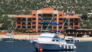 Un port de plaisance avec des bateaux amarrés, un immeuble doté de nombreux balcons et, au loin, une plage.