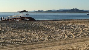 Une plage avec une jetée en bois et un espace de repos abrité.