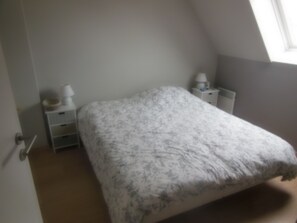 Une chambre à coucher avec un lit, une table de chevet, une lampe et une fenêtre.