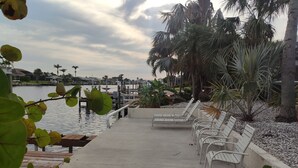 A waterfront promenade with benches and palm trees. - Vacation Pool Home - On 200ft Wide, Sailboat access Canal - SE Cape Coral! (Cape Coral)