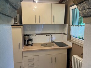 A compact kitchen with a built-in stove, a sink, and a window with a view. - small cozy, lovingly furnished holiday house for 2 people (Dresden)