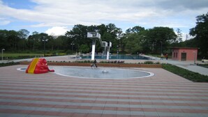 A public park with a central fountain, a playground with a red and yellow slide, and a small red building. - small cozy, lovingly furnished holiday house for 2 people (Dresden)