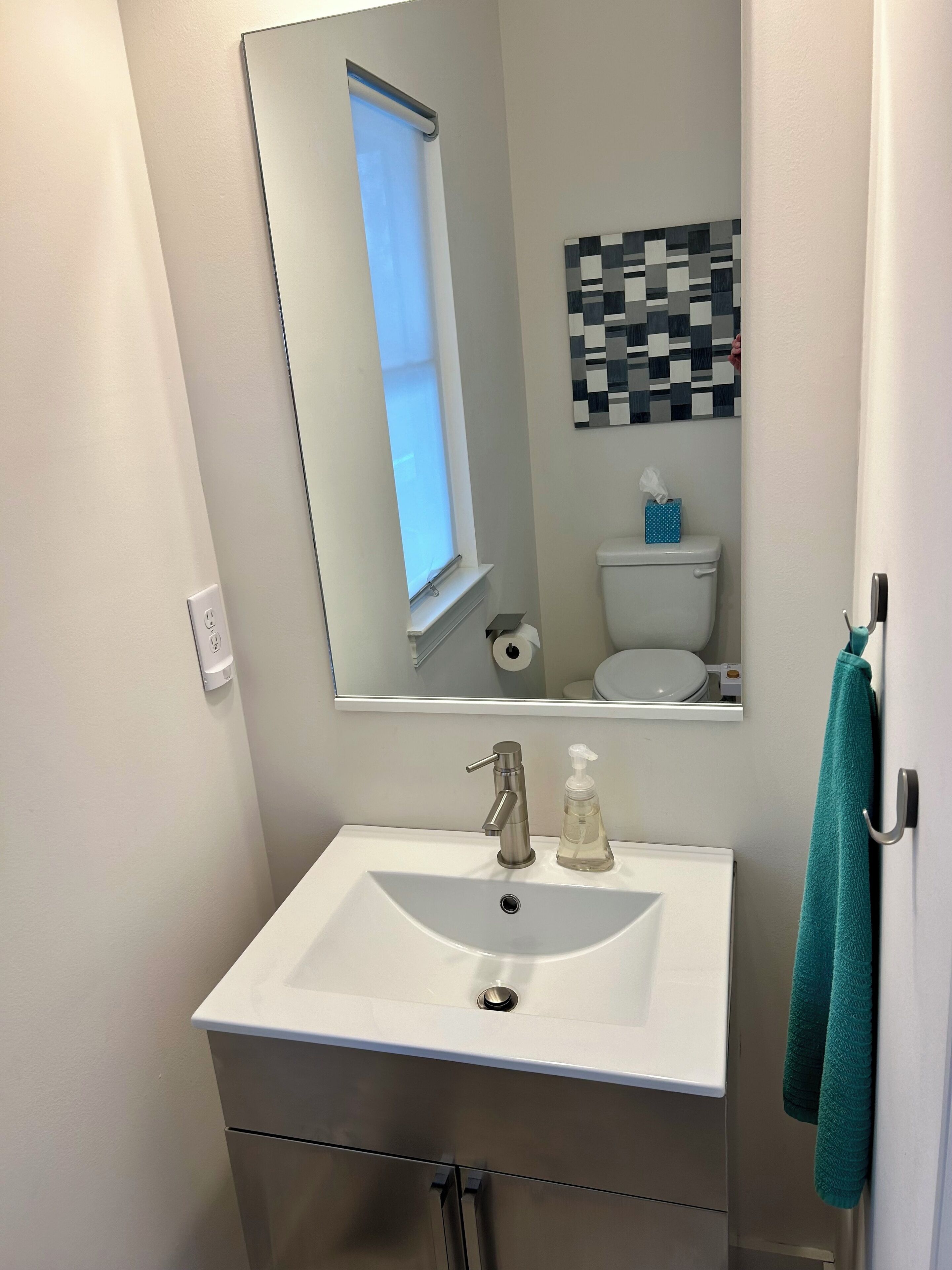 Ein Badezimmer mit weißem Waschbecken, einem Spiegel, einer Toilette und einem Handtuchhalter.