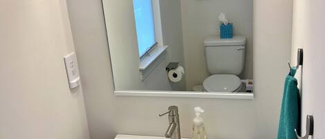 Ein Badezimmer mit weißem Waschbecken, einem Spiegel, einer Toilette und einem Handtuchhalter.