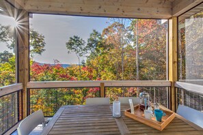 Une terrasse en bois avec une table dressée pour deux personnes, donnant sur une forêt aux couleurs automnales.
