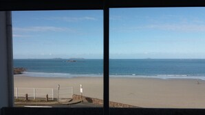 A beach view from a window, including the sea, a sandy shore, and a rocky outcrop in the distance. - LES PIEDS DANS L'EAU sea at 15 meters PANORAMIC VIEW PERROS GUIREC (PERROS GUIREC)