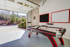 A billiards table in a room with a large window, a dartboard, and two framed artworks on the wall.