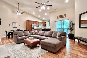 A spacious living room with a sectional sofa, a coffee table, and a dining area.