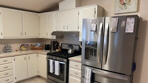Une cuisine moderne avec des armoires blanches, des appareils en acier inoxydable et une cuisinière à gaz.