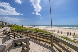 A wooden boardwalk leading to a beach with a clear sky.