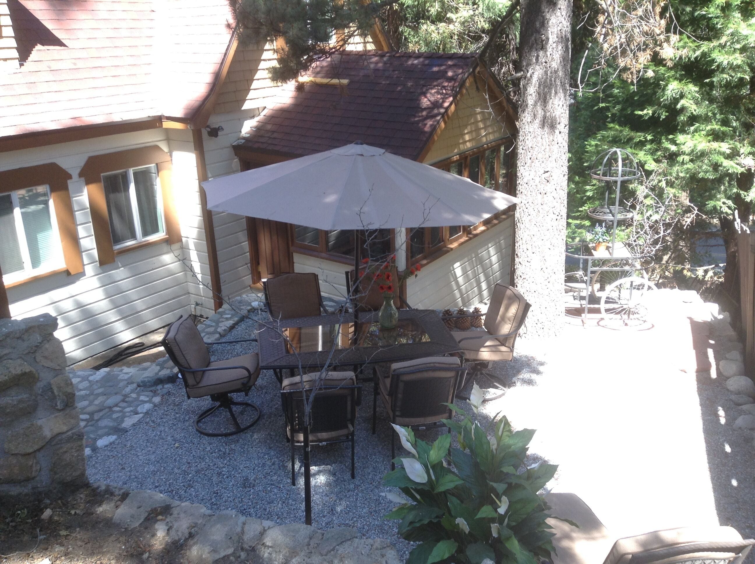 Une terrasse extérieure avec une table et des chaises, entourée d’un mur de pierre et d’une clôture en bois.