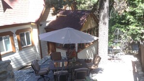 Un patio al aire libre con una mesa y sillas, rodeado por un muro de piedra y una valla de madera.