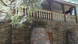 Un edificio de piedra con un balcón de madera y un pilar de piedra.