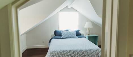 A bedroom with a bed, a nightstand, and a window.