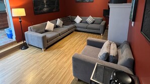 A living room with a sectional sofa, a small table, and a radiator. - Chesterman Beach Fine Art Vacation House - Walking distance to North Chesterman (Tofino)