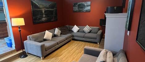 A living room with a sectional sofa, a small table, and a radiator.