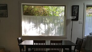 A dining area with a table and four chairs, a window with sheer curtains, and a view of trees outside. - Chesterman Beach Fine Art Vacation House - Walking distance to North Chesterman (Tofino)