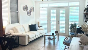 Un salon spacieux avec un canapé blanc, une table basse en bois et un ventilateur de plafond.
