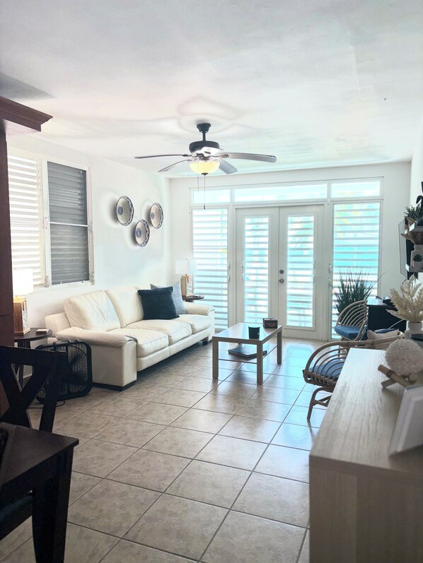 A spacious living room with a white sofa, a wooden coffee table, and a ceiling fan.