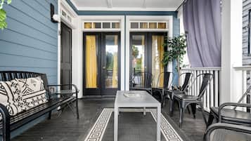 A covered porch with a bench, chairs, and a table.