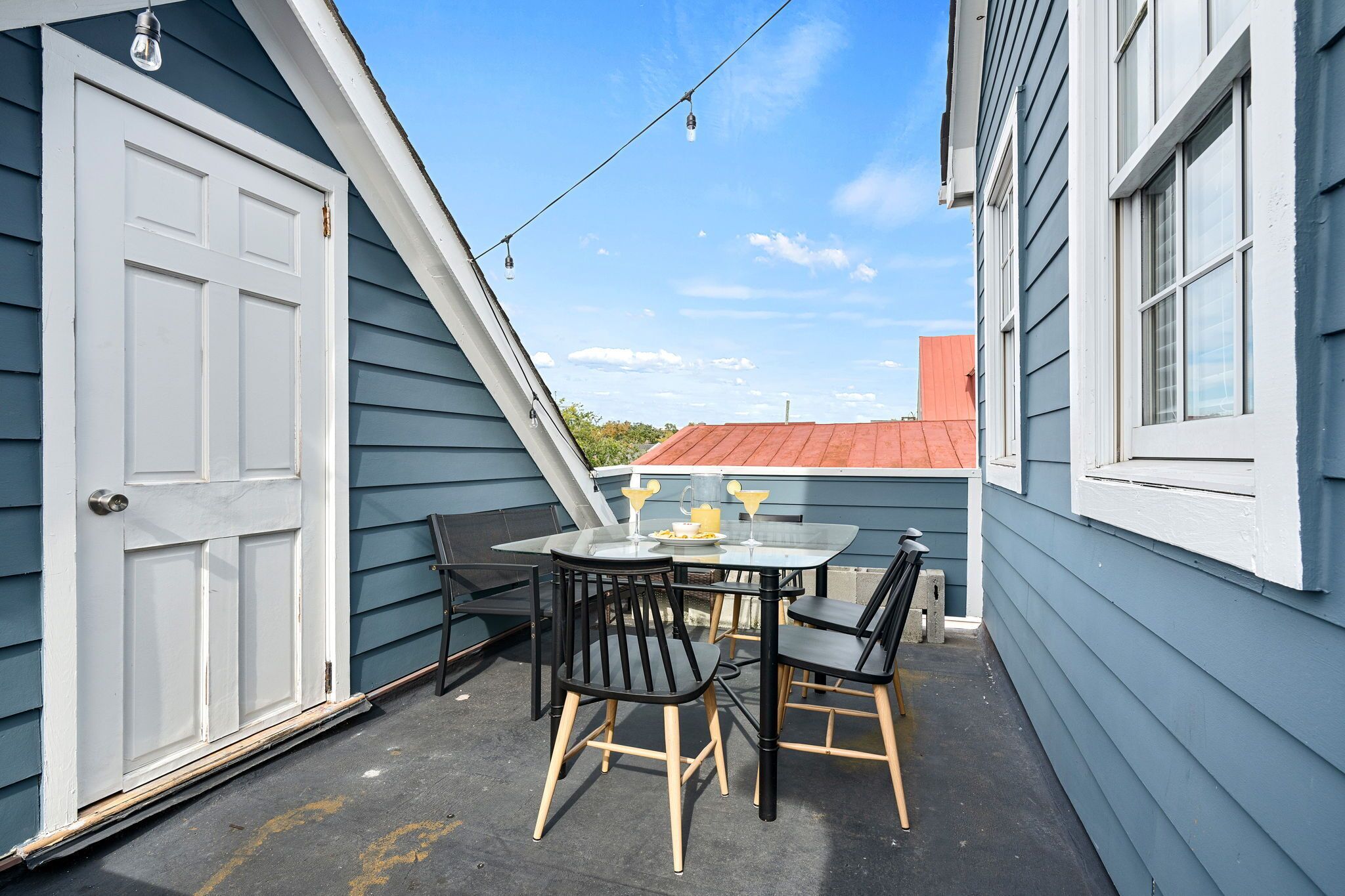 A small patio with a table and chairs, a door, and a string of lights.