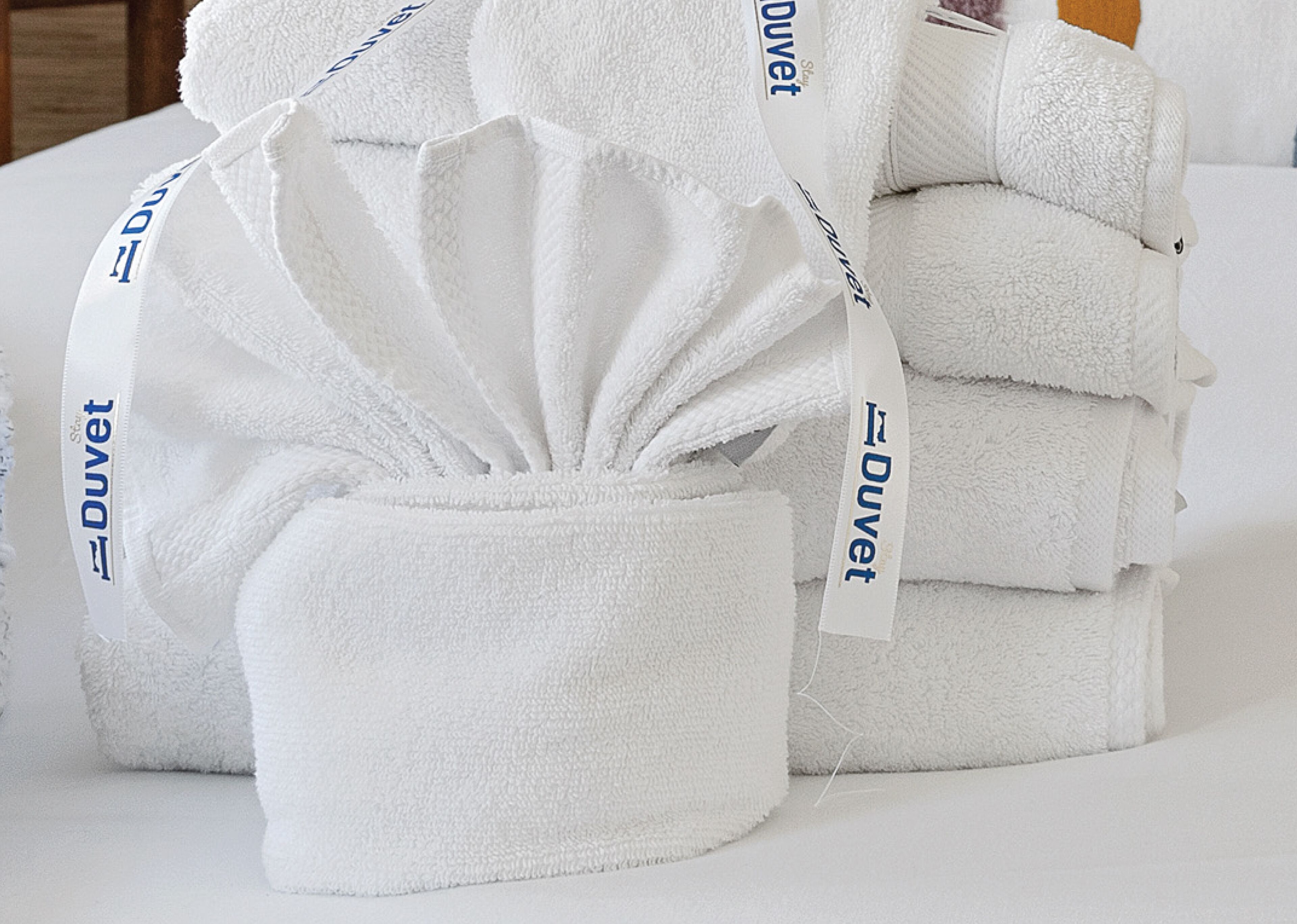 A stack of white towels with 'Duvet' printed on them.