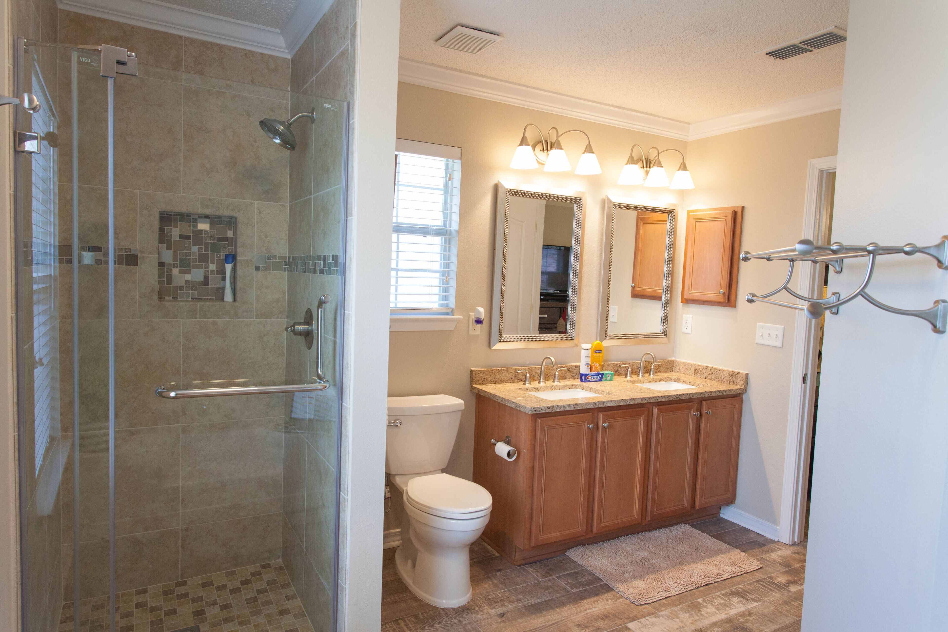 A bathroom with a glass-enclosed shower, a toilet, a sink with a vanity, and a mirror above the sink.