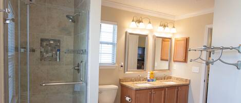 A bathroom with a glass-enclosed shower, a toilet, a sink with a vanity, and a mirror above the sink.