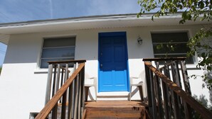 A white building with a blue door and wooden stairs leading to a porch. - Private home, North End LBK. 2 Bedrooms 1 Bath On 2nd Floor only steps to beach (Longboat Key)