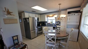A compact kitchen with a refrigerator, stove, microwave, and a dining table with chairs. - Private home, North End LBK. 2 Bedrooms 1 Bath On 2nd Floor only steps to beach (Longboat Key)