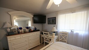 A bedroom with a bed, dresser, desk, chair, television, and a window with curtains. - Private home, North End LBK. 2 Bedrooms 1 Bath On 2nd Floor only steps to beach (Longboat Key)