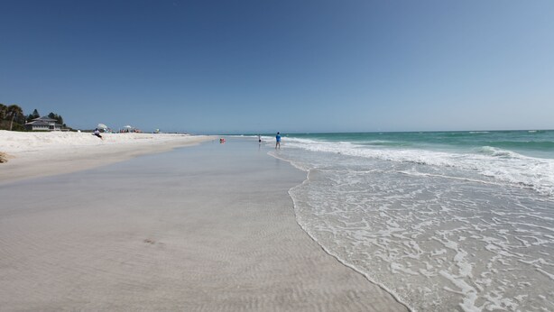 A wide, sandy beach with gentle waves and a clear blue sky. - Private home, North End LBK. 2 Bedrooms 1 Bath On 2nd Floor only steps to beach (Longboat Key)