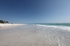 A wide, sandy beach with gentle waves and a clear blue sky. - Private home, North End LBK. 2 Bedrooms 1 Bath On 2nd Floor only steps to beach (Longboat Key)