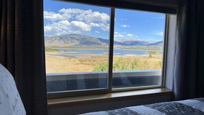 A room with a large window offering a view of a lake, mountains, and a clear sky. - On Lake Dillon with Amazing Views Everywhere! Hot Tub, Grill, Private Balcony! (Frisco)
