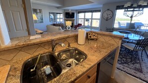 A kitchen with granite countertops, stainless steel sink, and a dining area with a chandelier. - On Lake Dillon with Amazing Views Everywhere! Hot Tub, Grill, Private Balcony! (Frisco)