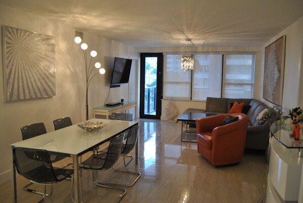 A modern living room with a dining area, a sofa, and a TV.