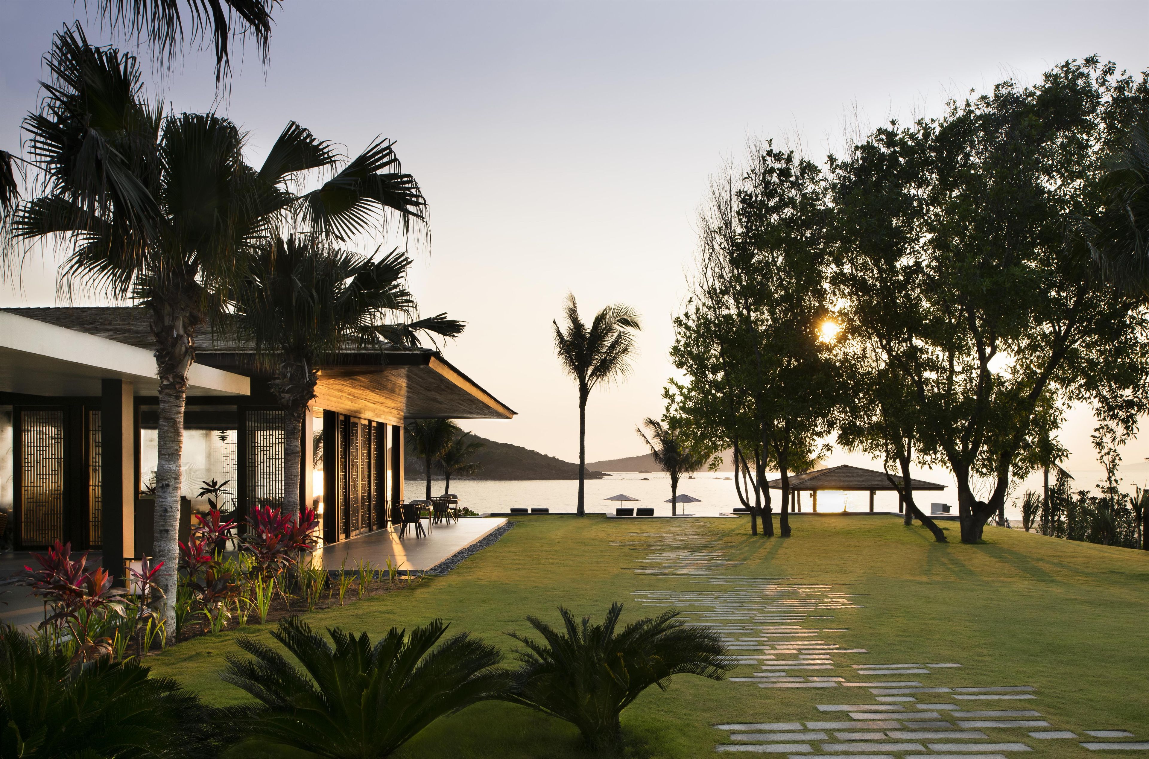 Resort com piscina, espreguiçadeiras e vista para o mar.