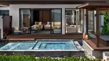 Una casa moderna con piscina, grandes puertas de vidrio y un área de patio.