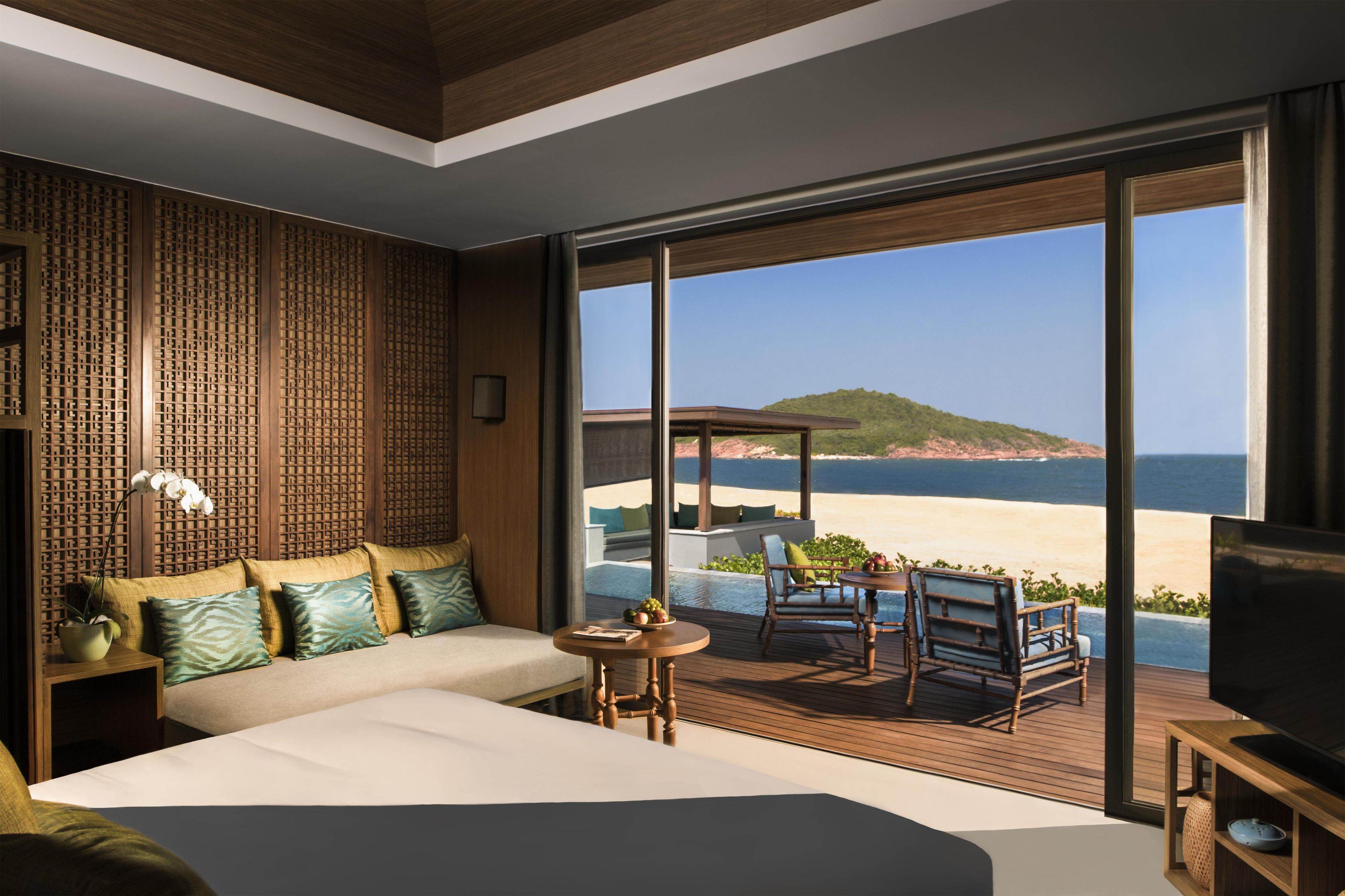 A hotel room with a large bed, a seating area with a table, and a view of the beach and ocean.