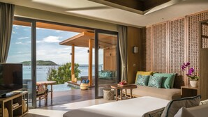 Habitación de hotel moderna con una cama grande, televisión, balcón con vista al mar y un separador de madera.