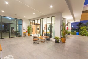 A modern indoor space with glass walls, a seating area with tables and chairs, and potted plants. - Donchan Grand Hotel (Chiang Mai)