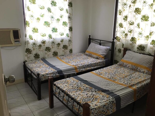 A room with two single beds, each with a patterned bedspread and a headboard.