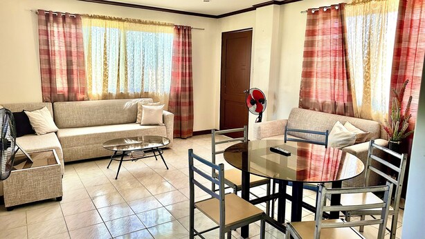 A living room with a sofa, coffee table, and dining table with chairs. - Cranberry's Place (Iloilo)